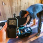 A first person perspective of a person using an indoor air quality monitor device, checking for allergens, particles and CO2 during a domestic home inspection.