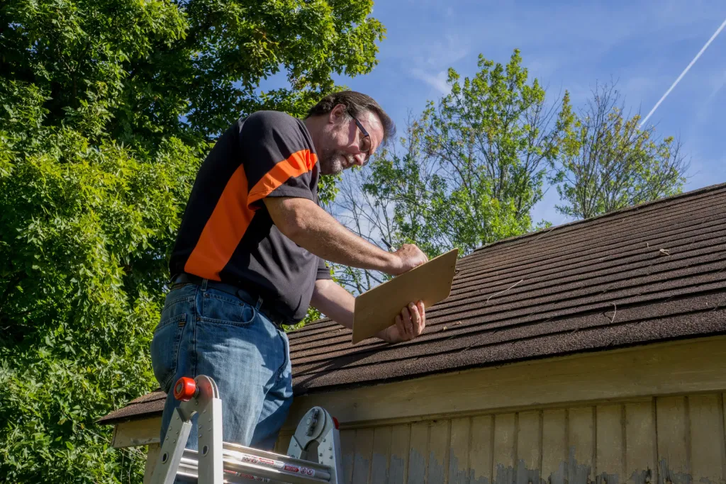 Contractor using a clipboard to figure our repiar cost for hail damaged roof.